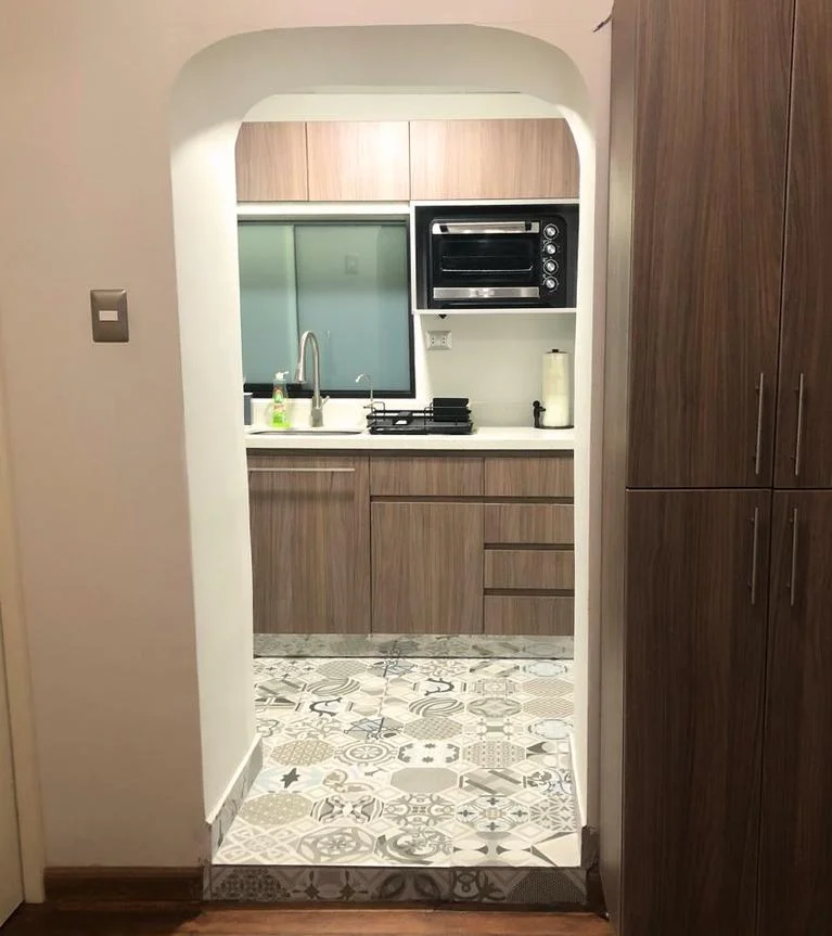 Acceso a cocina (fotografía) — arco blanco enmarcando la cocina terminada y suelo de porcelanato
